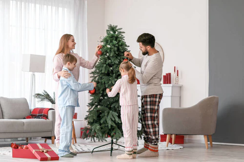 快乐的父母和他们的孩子在家里装饰圣诞树图片