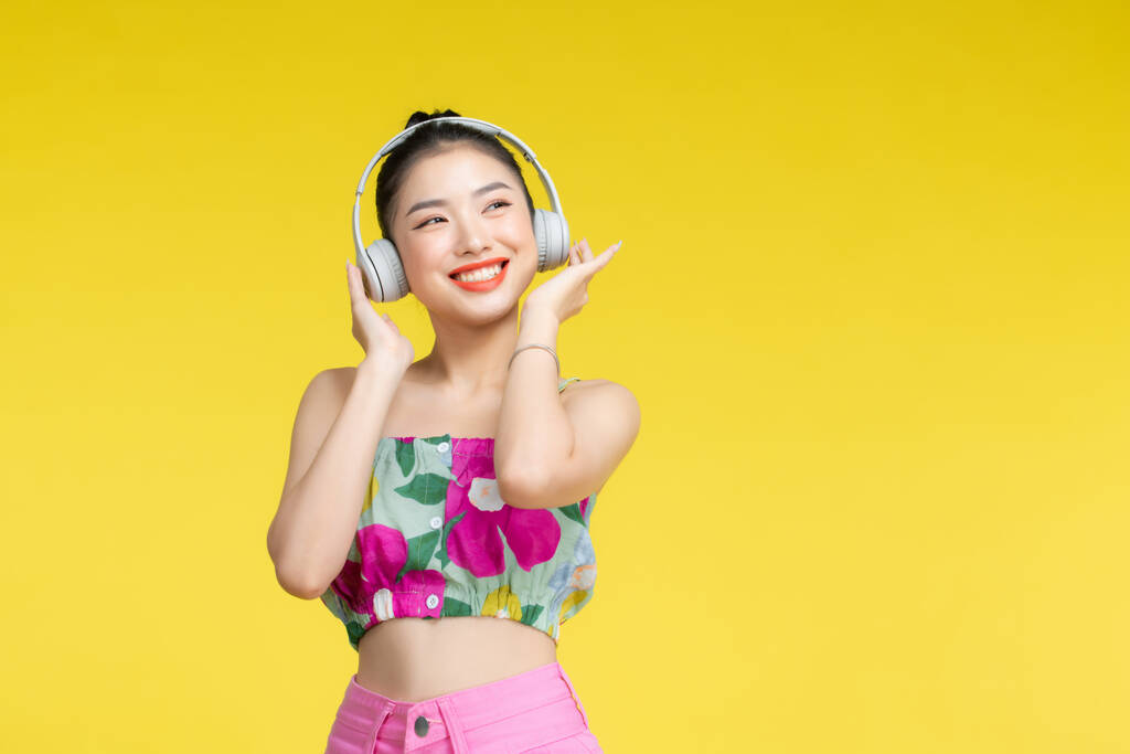 黄色背景下戴耳机的亚洲美女.图片