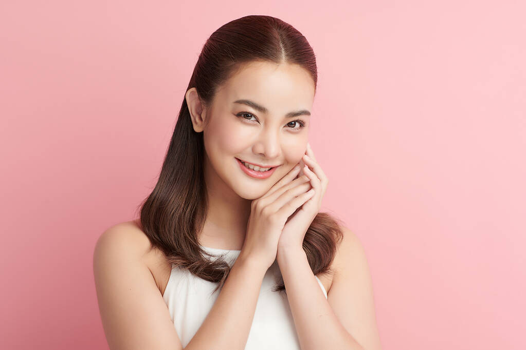 年轻美丽的亚洲女人，皮肤清澈，粉红背景，面部护理，面部护理，美容，美容美发，水疗，亚洲女性肖像.