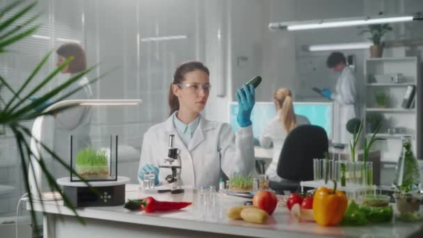 一名妇女检查了一个绿色新鲜黄瓜样本，并将数据写入数字平板电脑。青苗、蔬菜、水果的研究，以及实验室产品基因改造的研究。A图片