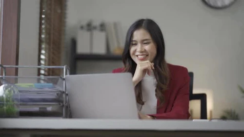 笑容满面的亚洲女人，穿着休闲装的漂亮女会计师，忙于处理文档、图表、纸张、办公室笔记本电脑，以及成功的金融界女商人图片