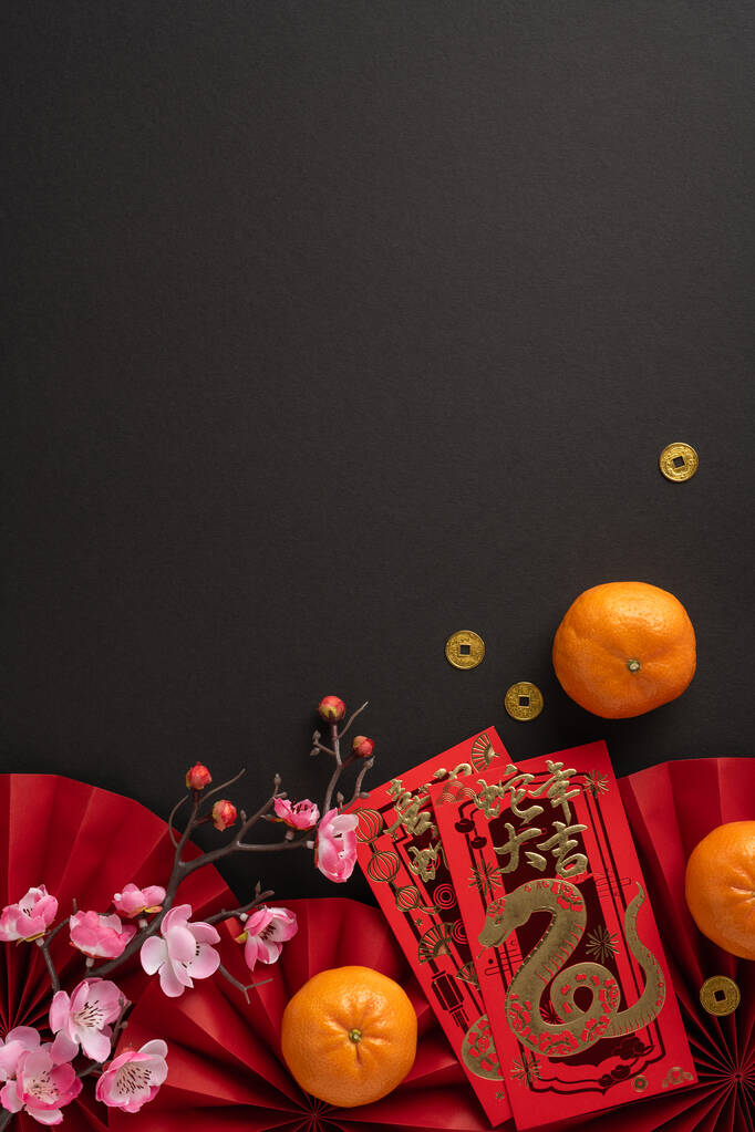 喜庆的中国新年垂直平铺着红色的信封，新鲜的橙子和樱花在黑暗的背景。这张照片捕捉了传统元素和欢乐的庆祝活动
