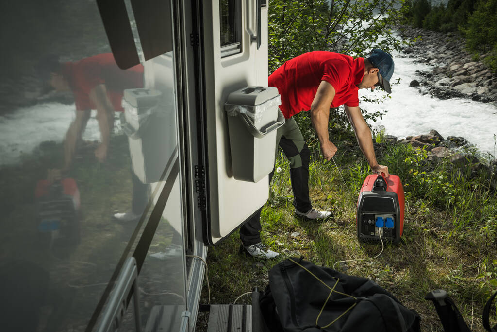高加索人在离网野营期间发射气体倒置便携式变频器发电机来吊起他的野营车.图片