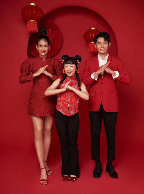 喜庆的亚洲家庭，身穿红色休闲装，举手投足，祝贺您在新的2024年装饰传统的红色背景.