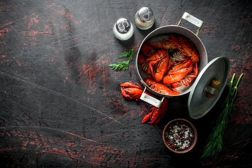 红色煮熟的小龙虾在平底锅与香料和萝卜。在黑暗的质朴背景图片