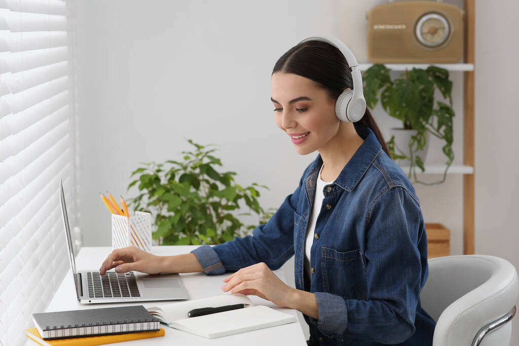 在家里用笔记本电脑学习的戴耳机的女人。在线翻译课程