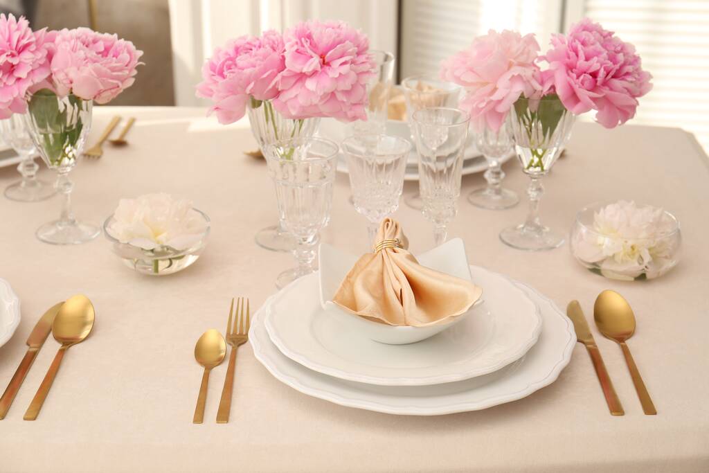 室内有精美的牡丹和面料餐巾的精致餐桌布置图片