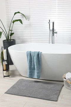带有浴缸、室内植物和柔软的浅灰垫子的时尚浴室内部图片