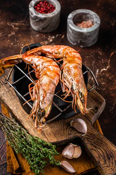 BBQ roasted Giant shrimps Langoustine on grill with herbs. Dark background. Top view.图片