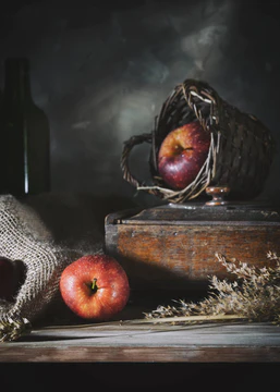 Red apples on a rustic table against a gray wall图片