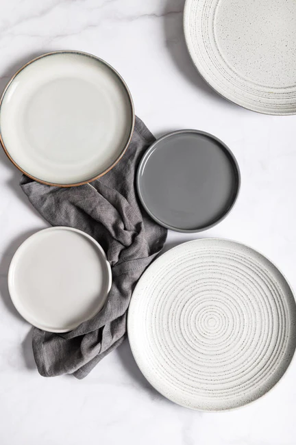 平铺着纹理波纹的空灰色陶瓷盘，灰色背景上有餐巾纸
