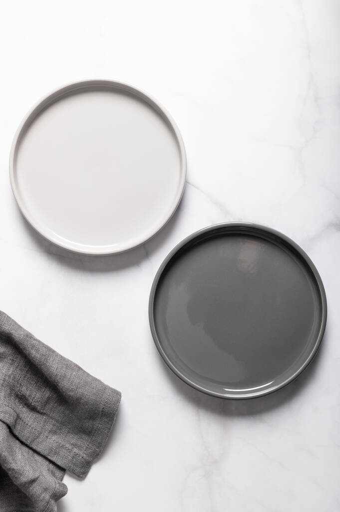 平铺着纹理波纹的空灰色陶瓷盘，灰色背景上有餐巾纸
