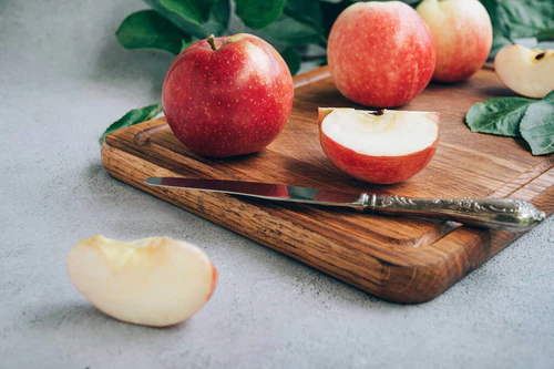 桌上木制切菜板上新鲜收获成熟的红色有机苹果的前景.图片