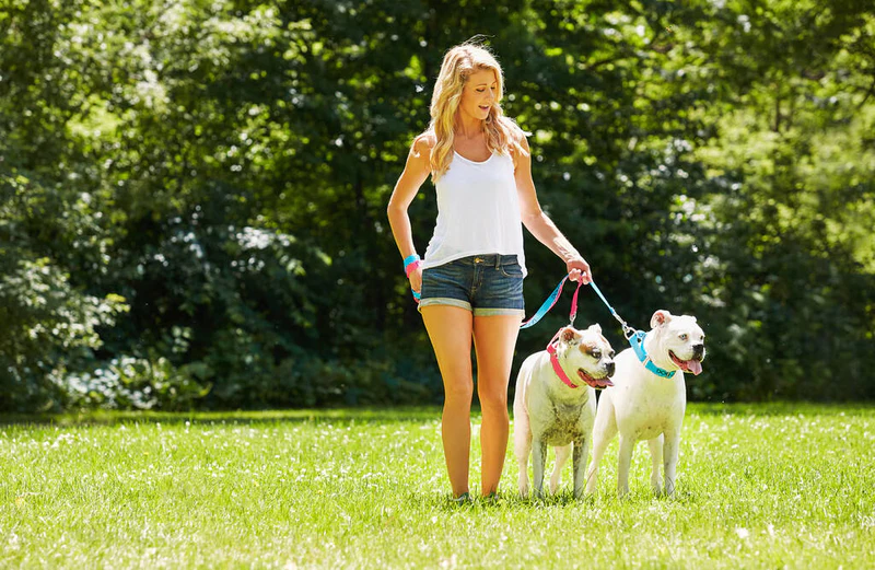 你的狗需要每天锻炼，你也是。一个带着两只狗在公园里的年轻女子