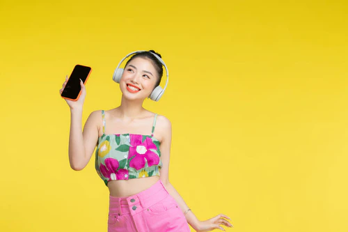 快乐微笑的年轻亚洲女人用智能手机放松，用无线耳机听音乐图片