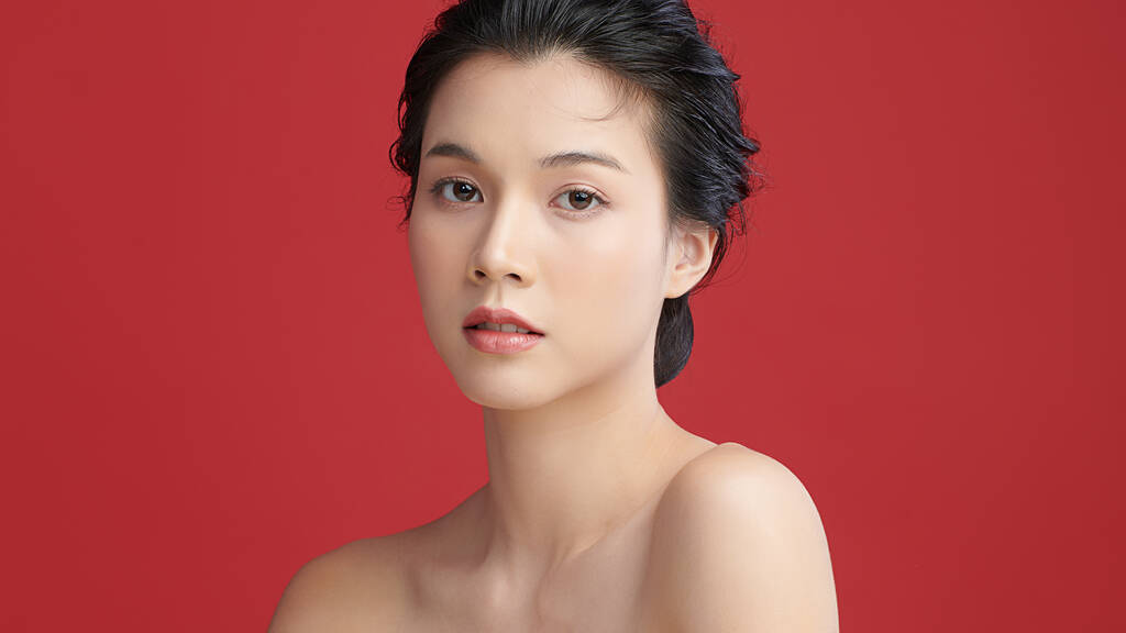 美丽的年轻亚洲女人，有着鲜红的背景、脸蛋护理、面部护理、美容美发、美容美发、水疗、亚洲女性肖像.