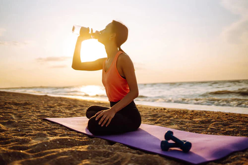 穿着运动服的年轻漂亮女子独自在野外海滩练瑜伽。健康生活方式概念图片